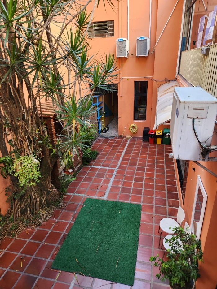 Pátio interno com piso de tijolinho, plantas e área de convivência